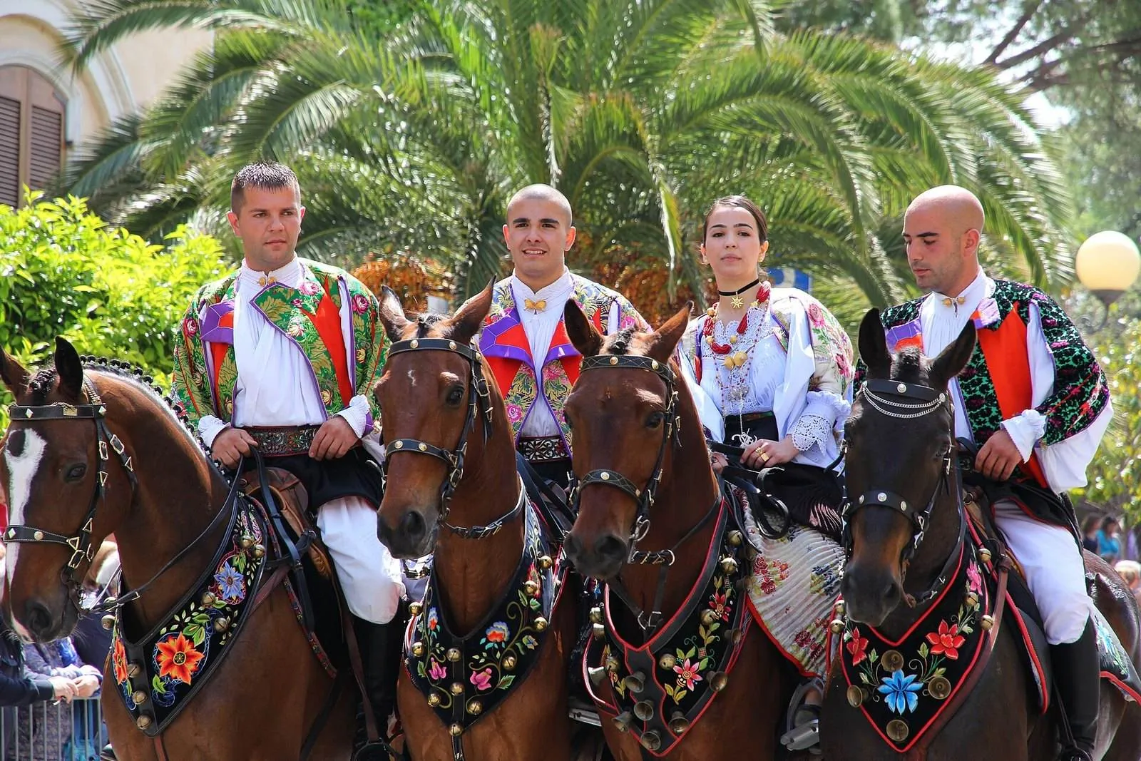 Uomini e donne in costume tradizionale sardo a cavallo