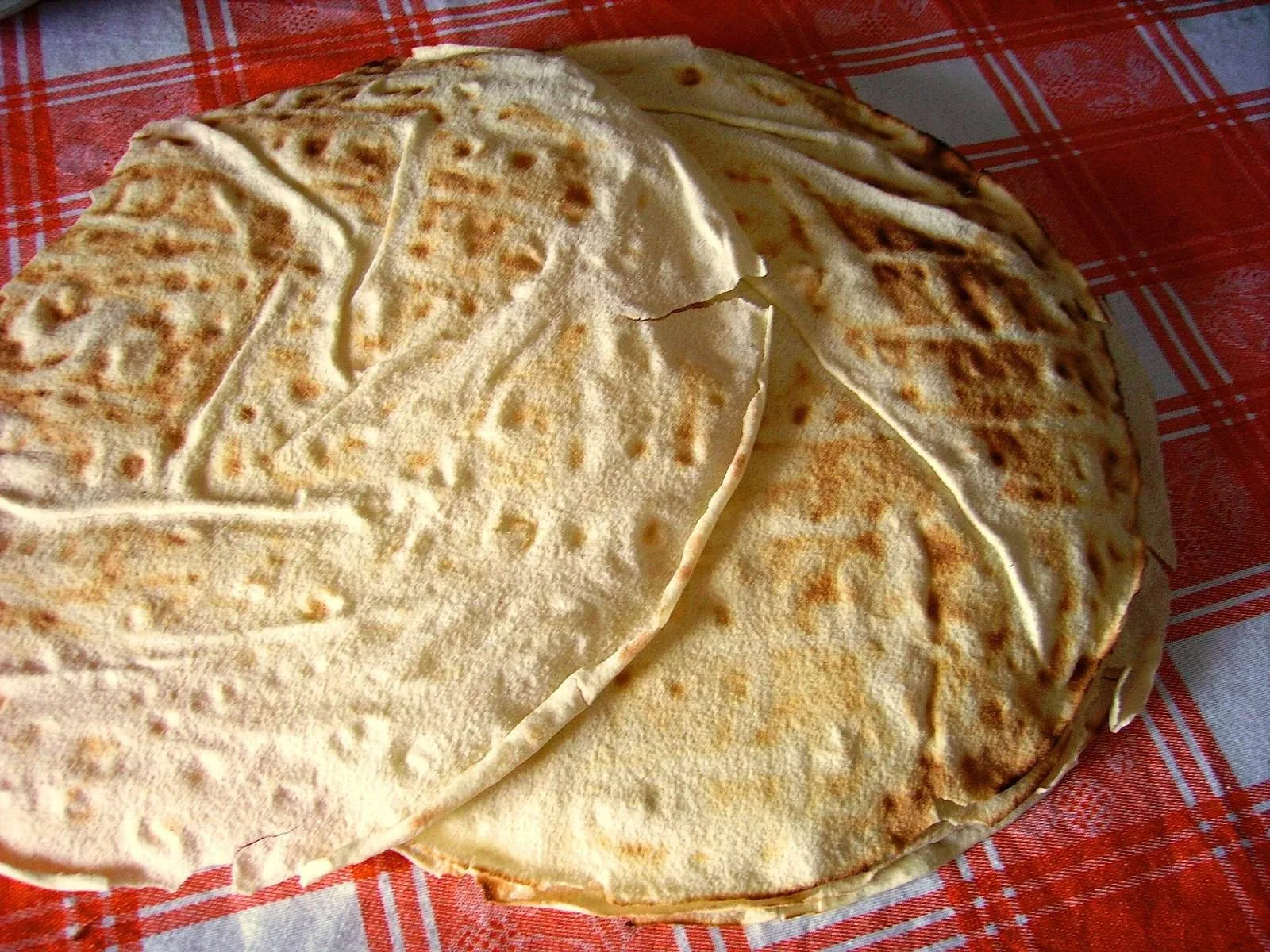 Un foglio di pane carasau appoggiato su una tovaglia a quadri